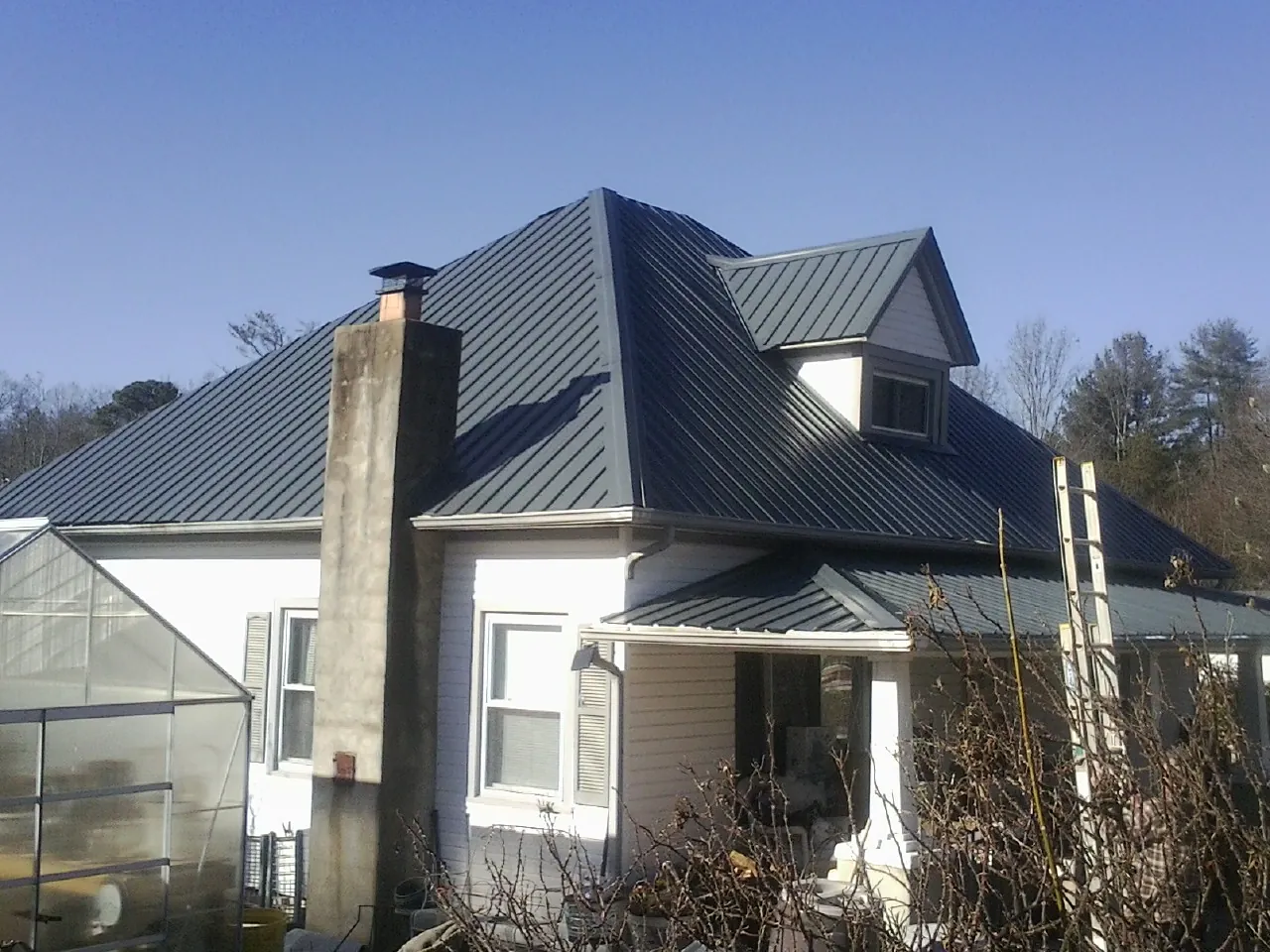 Dark blue standing seam metal roof on a white farmhouse with dormer — Slate & Tile Roof Repair by Roofing Brothers in Searcy