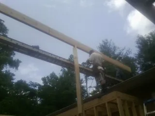 Carpenter setting a ridge beam over a new addition frame — Ice Dam Removal by Roofing Brothers in Searcy