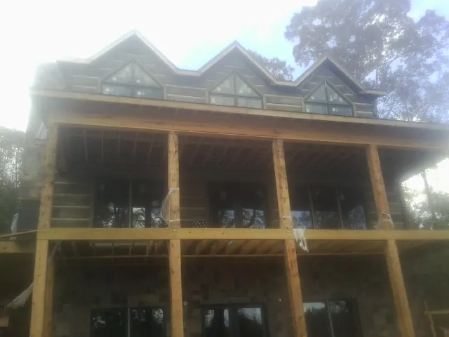 Dormers and porch framing on a large log home under construction — Roof Coating work by our crew in Searcy