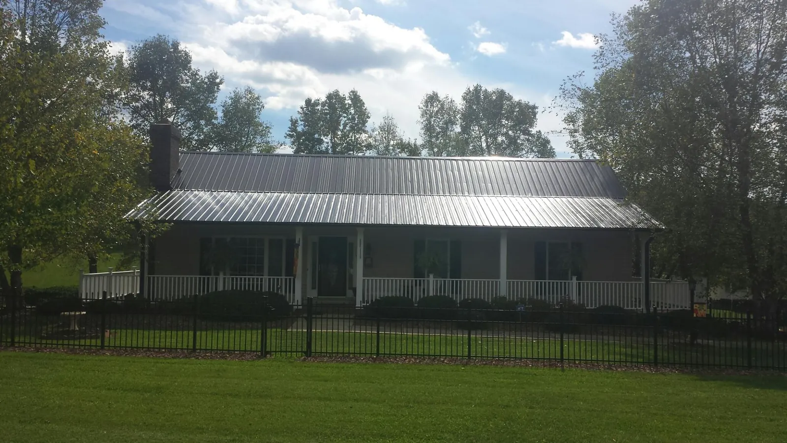 Gray metal roof on a brick ranch with a full width front porch — Gutter Guard Installation work by our crew in Searcy