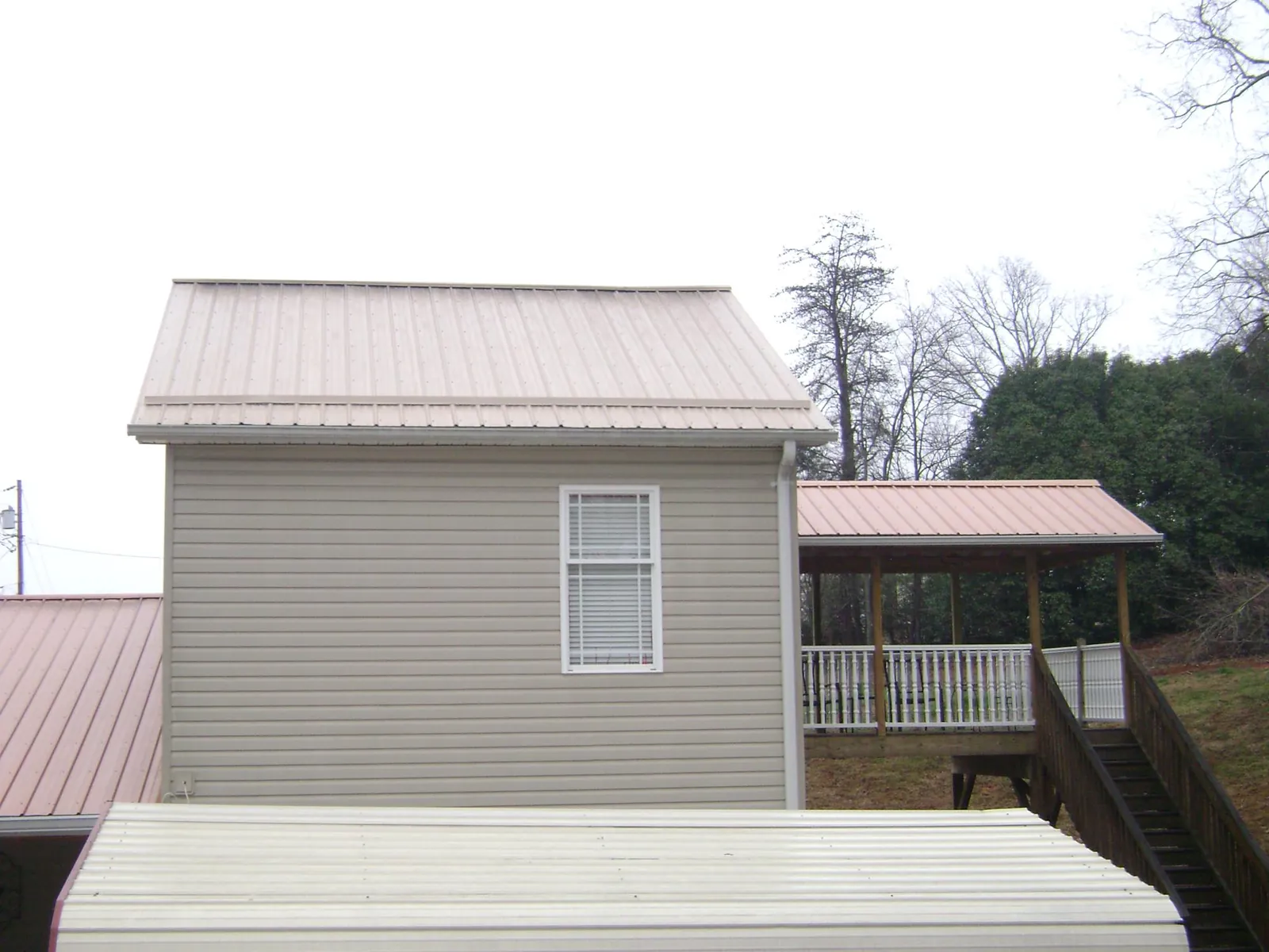 Tan metal roofs on a two story addition and attached porch, from a Roof Replacement job in Searcy