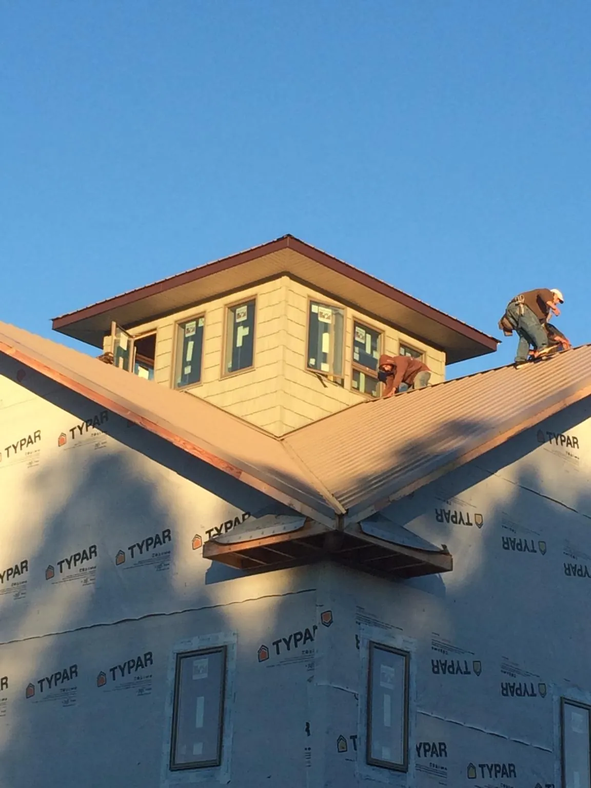 Roofers working around a rooftop cupola on a new metal roof at sunset — Roof Waterproofing in Searcy by Roofing Brothers